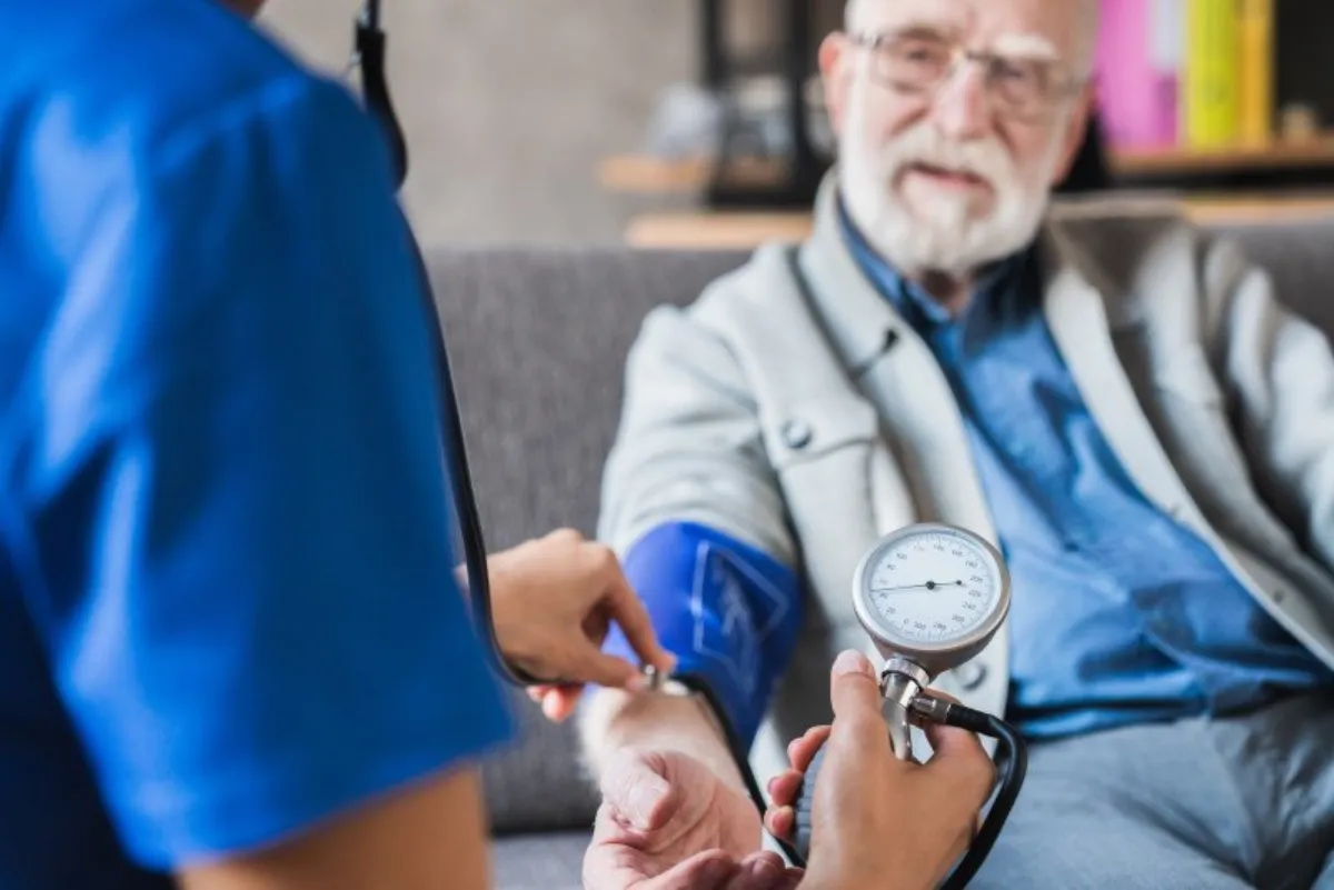 Pflegefachkraft misst den Blutdruck bei einem älteren Patienten
